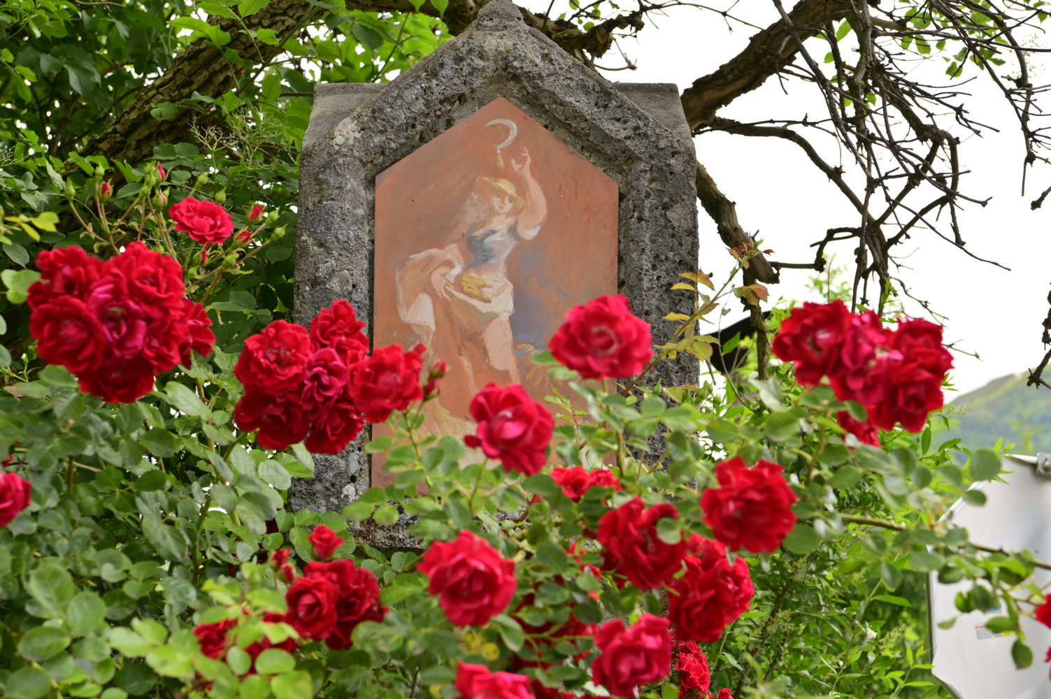 Blumengeschmücktes Marterl im Ort.